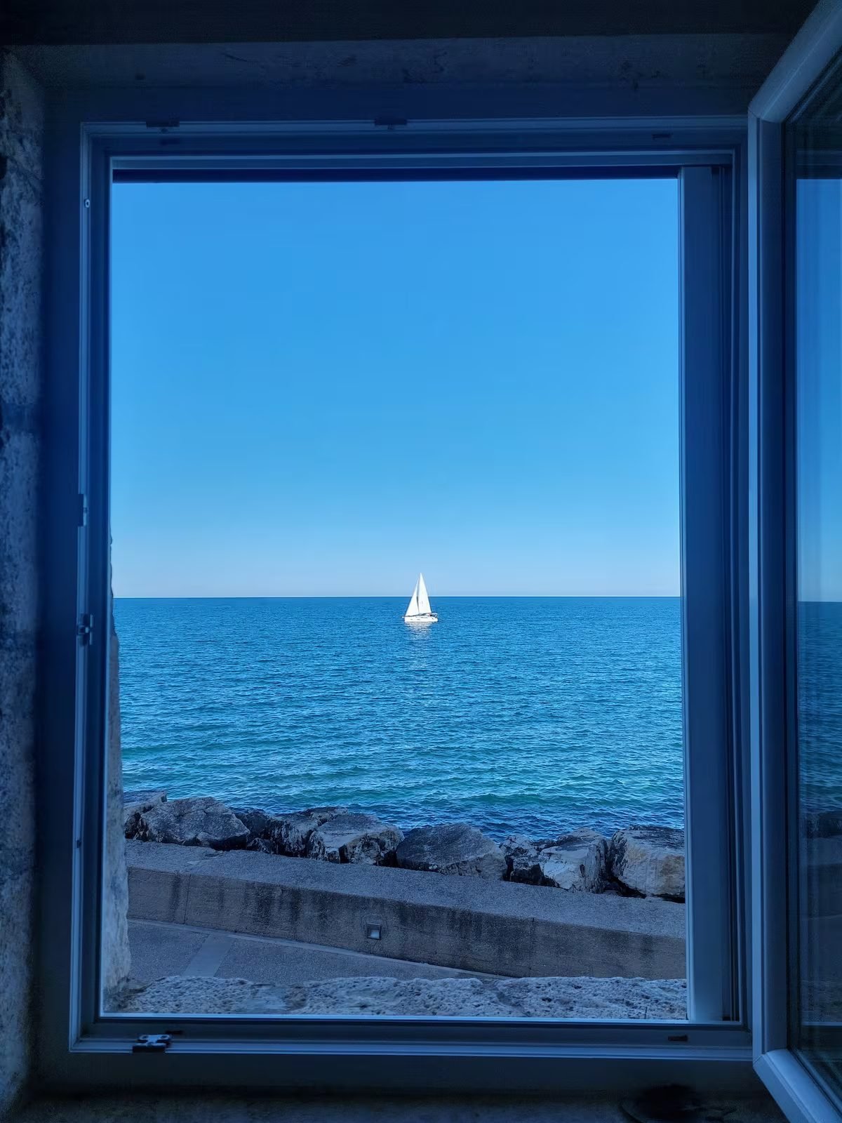 Vista dalla finestra con barca a vela